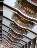 A high-angle view looking down into the tiered, curved balconies of a modern multi-story hotel atrium.