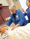 Two practitioners in blue lab coats perform Reiki energy healing on a patient in a hospital bed.