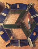 A stained glass Reiki crystal grid with various quartz points and stones arranged in a geometric pattern.