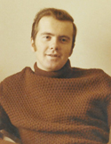 A vintage portrait of William Rand with sideburns wearing a brown textured turtleneck sweater.