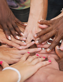 Many hands of diverse skin tones gathered together in a circle, overlapping at the center.
