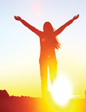 Silhouette of a woman with arms raised toward a bright, glowing sun at the horizon.