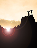 Silhouette of two people with raised arms standing on a mountain peak at sunset.