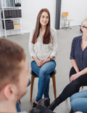 A group of people sitting in a circle on chairs in a bright, modern room during a discussion or workshop.