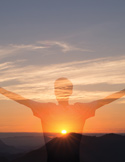 Silhouette of a person with arms outstretched towards a bright sunrise over a mountainous horizon.