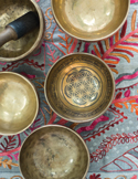 Top-down view of brass Tibetan singing bowls on a decorative embroidered cloth.