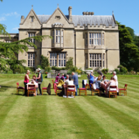 Students practicing Reiki on a sunny lawn in front of the Glastonbury Abbey House.